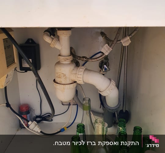 צנרת מתחת לכיור עם בקבוקי זכוכית